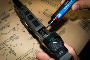 Applying Cerus Gear Freedom Lube to a handgun slide for cleaning, lubrication, and protection, with firearm schematic in the background.