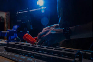 Person working on a rifle handguard installation under focused lighting, using a Cerus Gear AR15 gun cleaning mat and tools in a workshop setting.