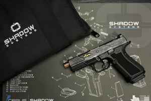Shadow Systems pistol displayed on a Cerus Gear gun cleaning mat featuring an exploded diagram of the firearm, next to a branded Shadow Systems case.